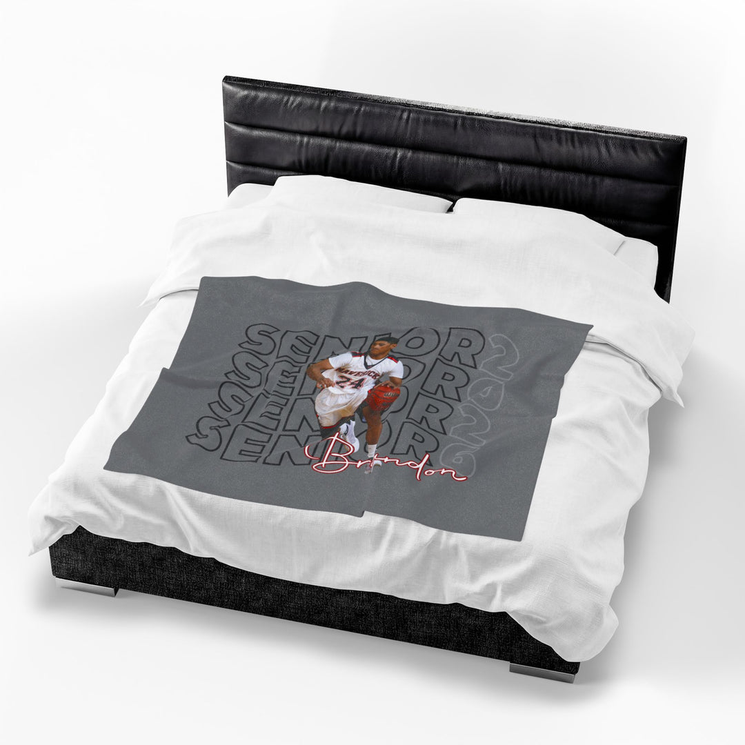 Gray blanket with a graphic design on a white bedspread with a black headboard.