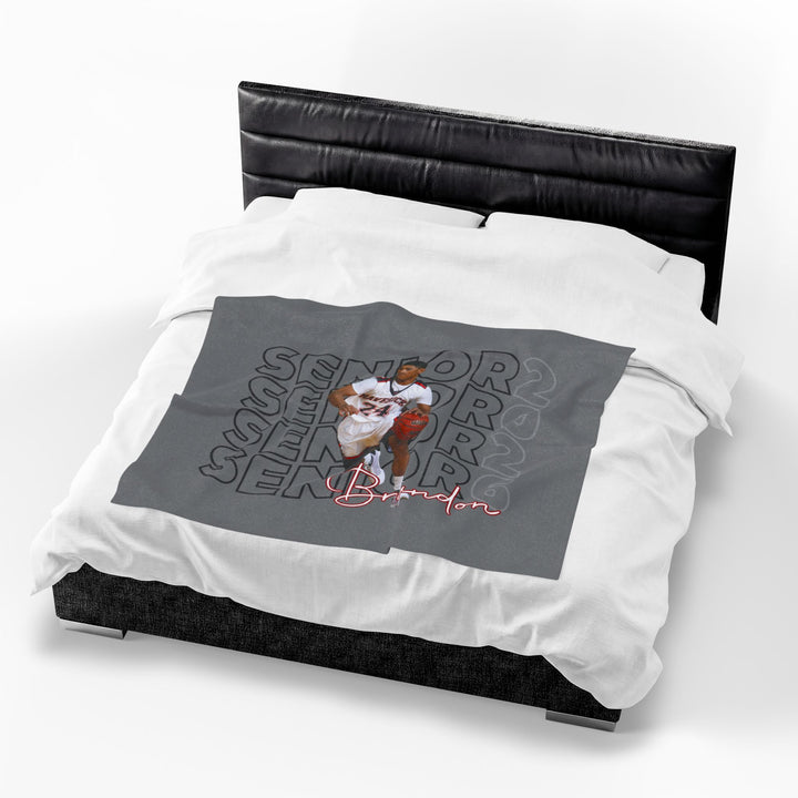 Gray blanket with a graphic design on a white bedspread with a black headboard.